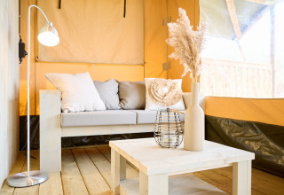 Intérieur d'une tente safari de luxe avec canapé, table basse et décoration au parc Krieghuusbelten.