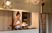 Woman serving breakfast with juice in a luxury safari tent kitchen at Familievakantiepark Krieghuusbelten.