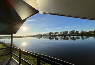 Vue depuis Waterlodge au Familievakantiepark Krieghuusbelten aux Pays-Bas, soleil et lac en reflet.