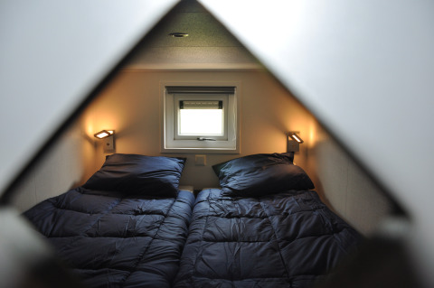 Vue de deux lits simples avec du linge bleu foncé dans un lodge Waterlodge à Krieghuusbelten.
