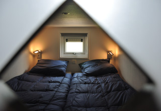 Vue de deux lits simples avec du linge bleu foncé dans un lodge Waterlodge à Krieghuusbelten.