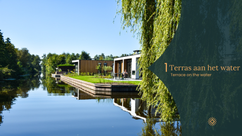 Moderne lodge met terras aan het water, omgeven door natuur en bomen onder een open blauwe lucht.
