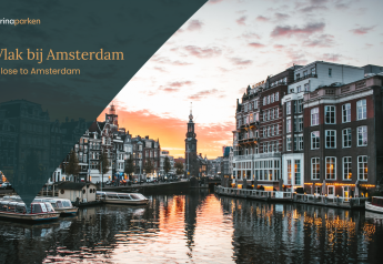 Zonsondergang over een kanaal vlak bij Amsterdam met boten en historische panden aan het water.