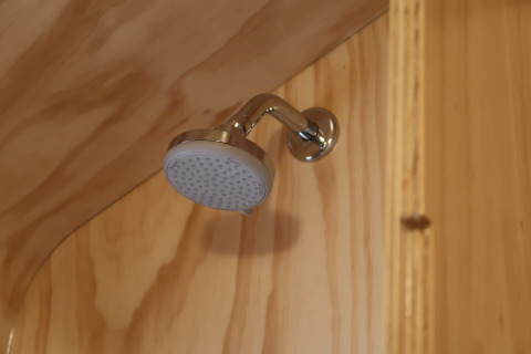 Soffione doccia nel bagno rivestito in legno della Wrap house con sauna e vasca, Resort de Parel, Paesi Bassi.