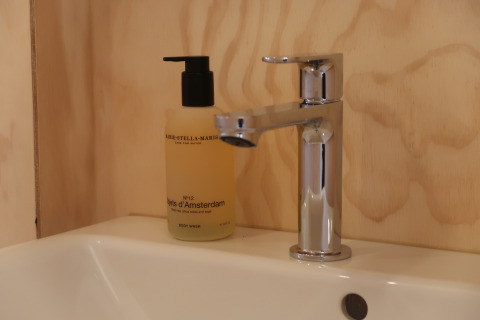 Moderne wastafel met chromen kraan en bodywash in Wrap house bij Resort de Parel, Nederland.
