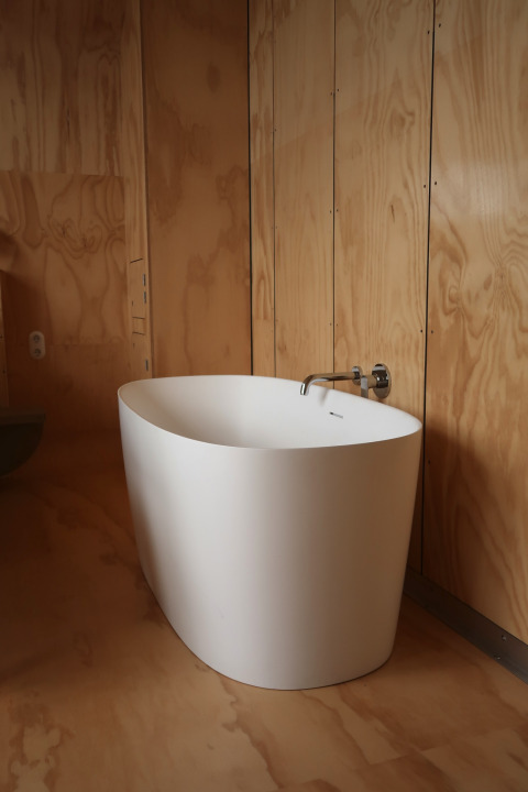 Vrijstaand bad in een modern houten badkamerinterieur bij Wrap house lodge, Resort de Parel, Nederland.