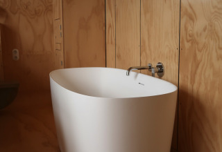 Vrijstaand bad in een modern houten badkamerinterieur bij Wrap house lodge, Resort de Parel, Nederland.