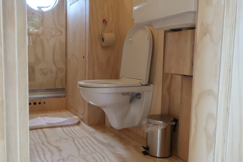 Badkamer met hangend toilet, wastafel en prullenbak bij Wrap house, Resort de Parel, Nederland.