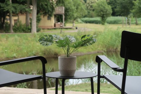 Ausblick von der Wrap house Lodge mit Sauna und Badewanne im Resort de Parel, zwei Stühle, Pflanze.