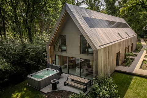Modern lodge with jacuzzi and large windows nestled in the woods at Woodz Lodges in Belgium, nature view.