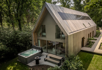 Moderne lodge met jacuzzi en grote raampartijen in het groen bij Woodz Lodges in België, bosrijke omgeving.