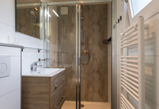 Moderne badeværelse i Eco Cottage på De Thijmse Berg, Holland, med brusekabine og træskab.