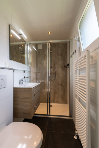 Baño moderno en Eco Cottage de De Thijmse Berg, Países Bajos, con ducha y muebles de madera.