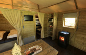 Interior of Kampeerlodge at Familievakantiepark Krieghuusbelten with beds, heater, and rustic decor.