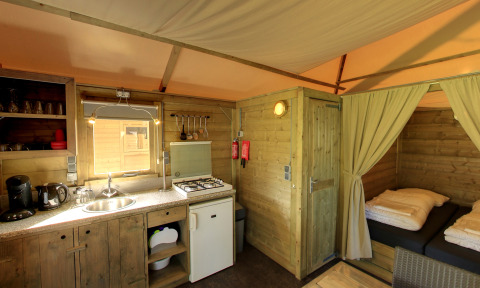 Innenaufnahme der Kampeerlodge im Familievakantiepark Krieghuusbelten mit Küche und Schlafbereich.