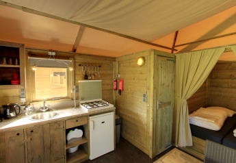 Interior of Kampeerlodge at Familievakantiepark Krieghuusbelten, showing kitchen and sleeping area.