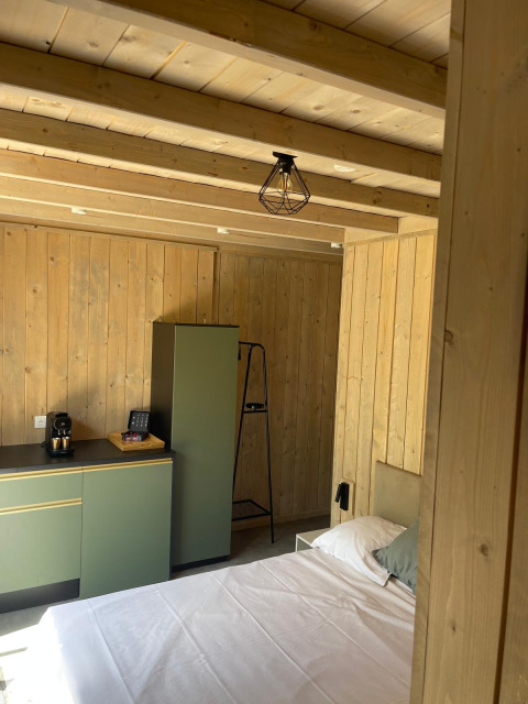 Chambre moderne en bois avec armoires vertes, lit et machine à café au Cocoon de l'Ourthe en Belgique.