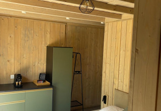 Chambre moderne en bois avec armoires vertes, lit et machine à café au Cocoon de l'Ourthe en Belgique.