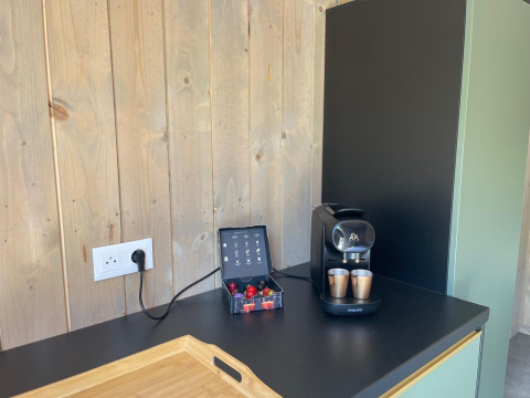 Machine à café, tasses et capsules sur un comptoir noir au Cocoon de l'Ourthe, Hameau de l'Ourthe, Belgique.