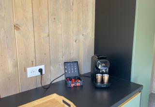 Machine à café, tasses et capsules sur un comptoir noir au Cocoon de l'Ourthe, Hameau de l'Ourthe, Belgique.