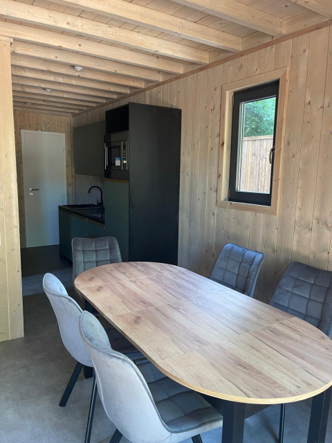 Interieur van Eco Lodge bij Hameau de l'Ourthe in België, met eettafel, stoelen en moderne keuken.