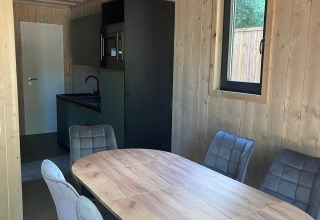 Interieur van Eco Lodge bij Hameau de l'Ourthe in België, met eettafel, stoelen en moderne keuken.