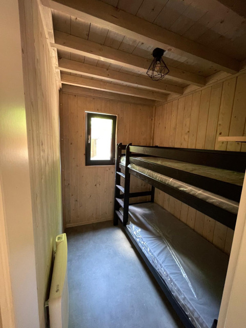Kleine kamer met stapelbedden in Eco Lodge, Hameau de l'Ourthe, België, met houten wanden.