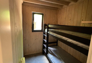 Kleine kamer met stapelbedden in Eco Lodge, Hameau de l'Ourthe, België, met houten wanden.