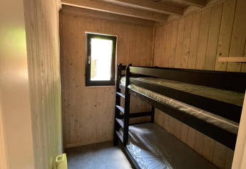 Kleine kamer met stapelbedden in Eco Lodge, Hameau de l'Ourthe, België, met houten wanden.