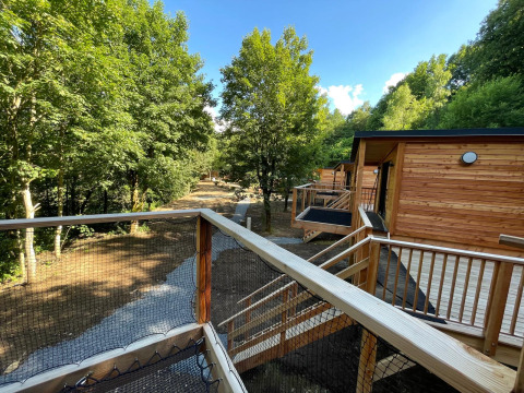 Zicht vanuit een boomhut in Hameau de l'Ourthe, België, met houten terras en bosrijke omgeving.