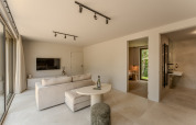 Bright, modern lodge living room with access to bedroom and bathroom, wall-mounted TV, and large windows.