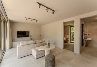 Helles, modernes Lodge-Wohnzimmer mit Zugang zum Schlafzimmer, Bad, TV und großen Fensterfronten.