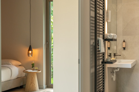 Lodge moderne avec chambre douillette et salle de bains élégante, serviettes et produits de toilette sur étagères.