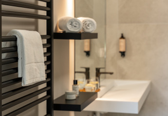 Elegant badeværelse på lodge med rene håndklæder, hylder med toiletartikler, moderne vask og spejl.
