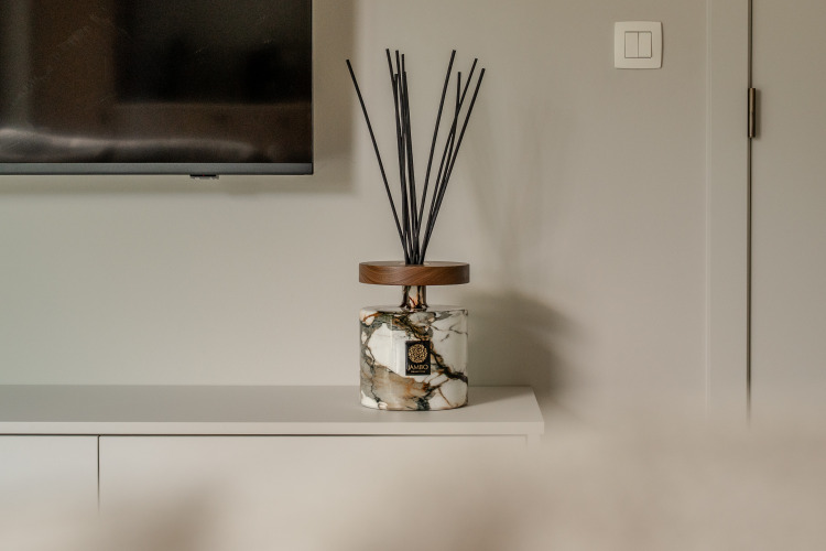 Difusor de fragancia de mármol con varillas negras sobre mueble blanco en Suite Accessible de Woodz Lodges, Bélgica.