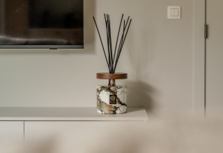 Difusor de fragancia de mármol con varillas negras sobre mueble blanco en Suite Accessible de Woodz Lodges, Bélgica.