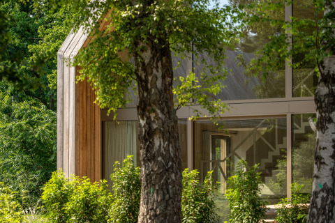 Moderne lodge bij Woodz Lodges in België met grote raampartijen en omgeven door veel groen.