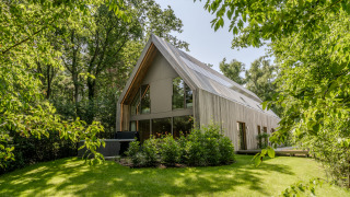 Moderne lodge met jacuzzi, omringd door weelderig groene bomen en gazon, in natuurlijk daglicht.