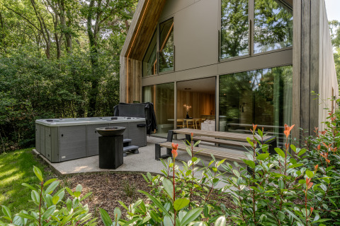 Outdoor patio at Lodge with Jacuzzi at Woodz Lodges in Belgium, surrounded by forest and modern design.