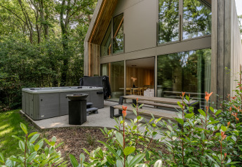 Buitenterras bij Lodge met jacuzzi bij Woodz Lodges in België, omgeven door bos en hedendaags design.