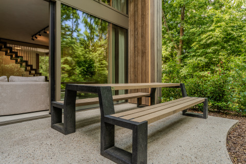 Modern patio with bench and table at a wood-paneled lodge surrounded by trees at Woodz Lodges, Belgium.