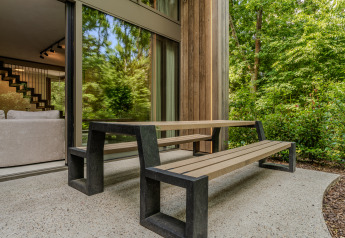 Moderne terras met zitbank en tafel aan een houten lodge in het bos bij Woodz Lodges, België.