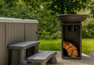 Outdoor jacuzzi with plastic steps and a fire pit, nestled near lush greenery at the Lodge with Jacuzzi.