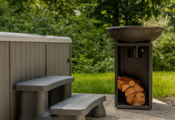 Buitenjacuzzi met kunststof trapje en vuurkorf ernaast, gelegen bij de Lodge met Jacuzzi in het groen.