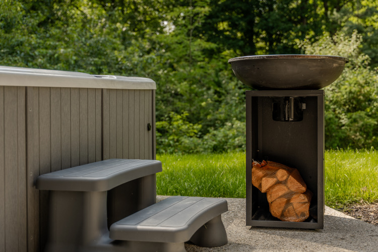 Jacuzzi exterior con escalones de plástico y fogón al lado, rodeado de vegetación en el Lodge.
