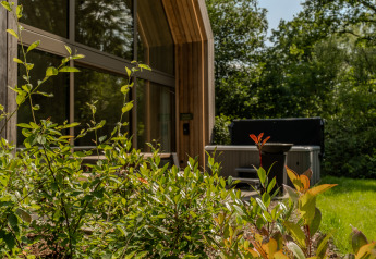 Moderne lodge met jacuzzi buiten en veel groen rondom, vastgelegd bij Lodge with Jacuzzi op een zonnige dag.