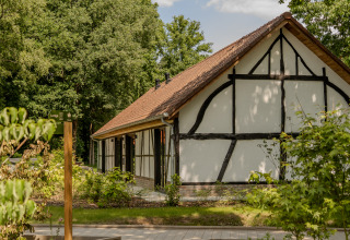 Authentieke lodge met jacuzzi en rood dak te Villa Lodge, Woodz Lodges, te midden van groen in België.