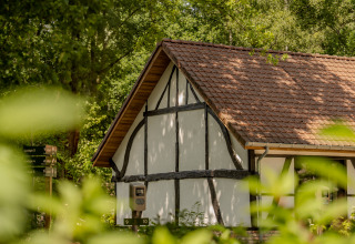 Traditionele villa lodge met jacuzzi en pannendak bij Woodz Lodges in België, omgeven door natuur.