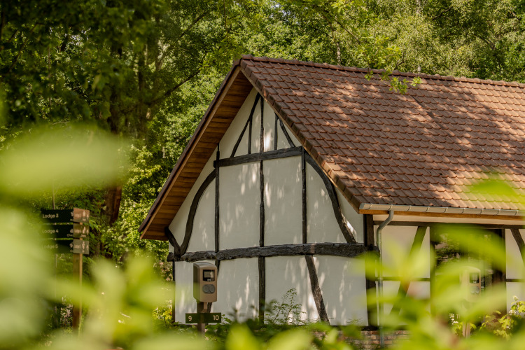 Traditionelle Villa-Lodge mit Jacuzzi und Ziegeldach bei Woodz Lodges in Belgien, umgeben von Natur.