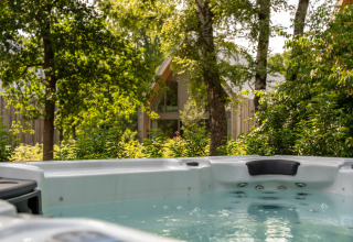 Buitenjacuzzi aan Villa Lodge bij Woodz Lodges in België, omgeven door bomen en natuur.
